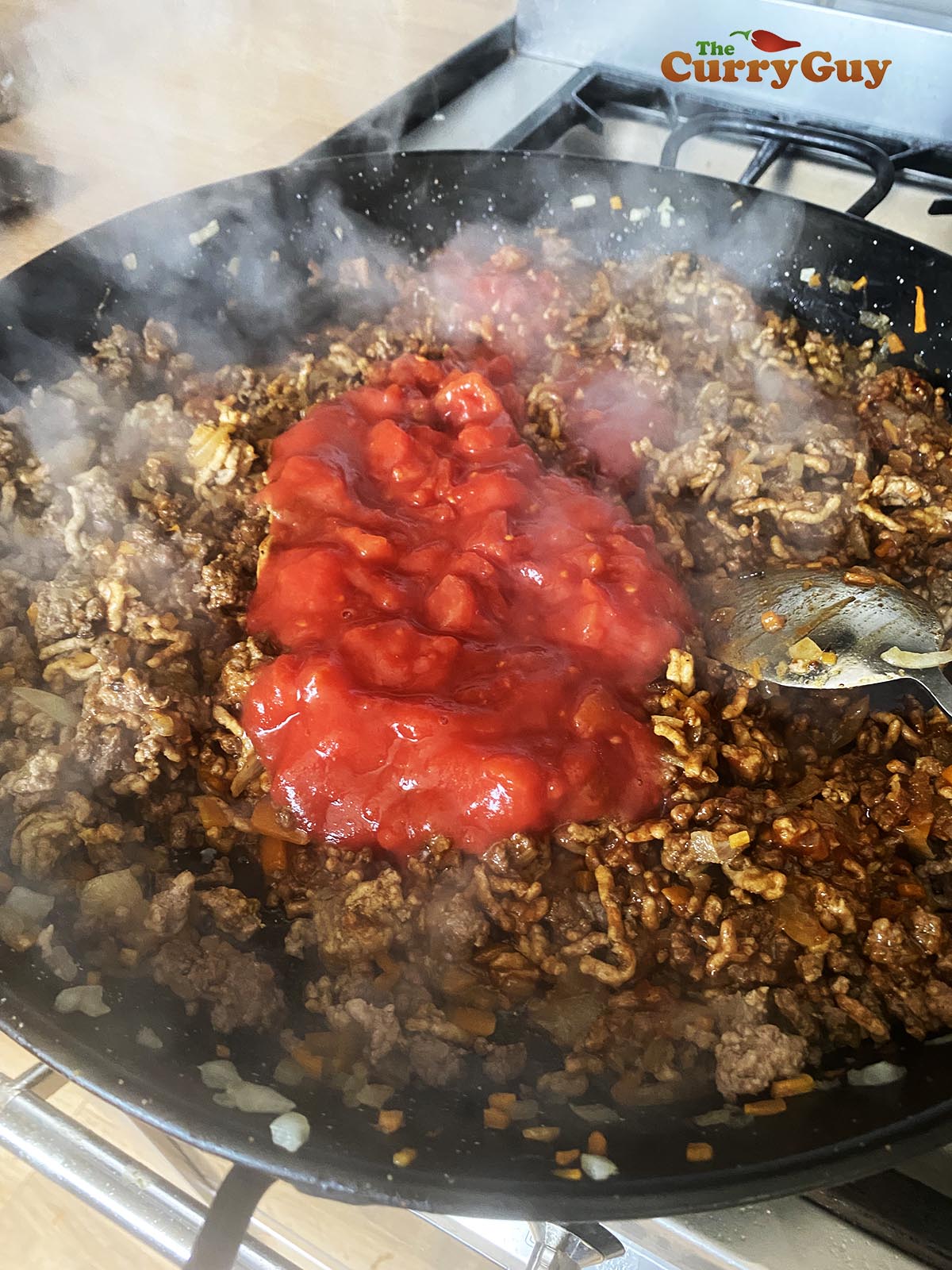 Cooking the meat down and adding the curry powder, stock, ketchup and Worcestershire sauce.