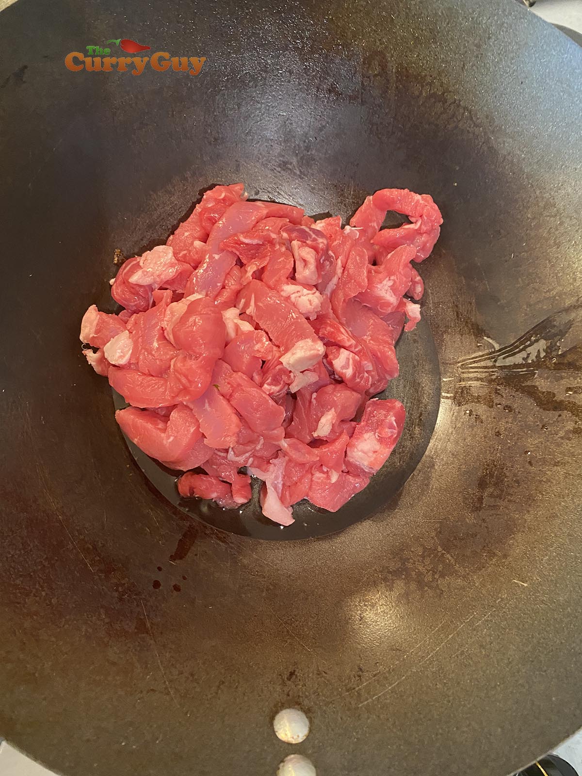 Adding meat to wok.