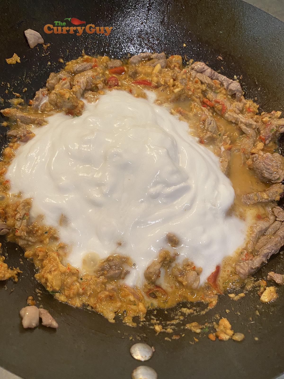 Adding coconut milk to pan.
