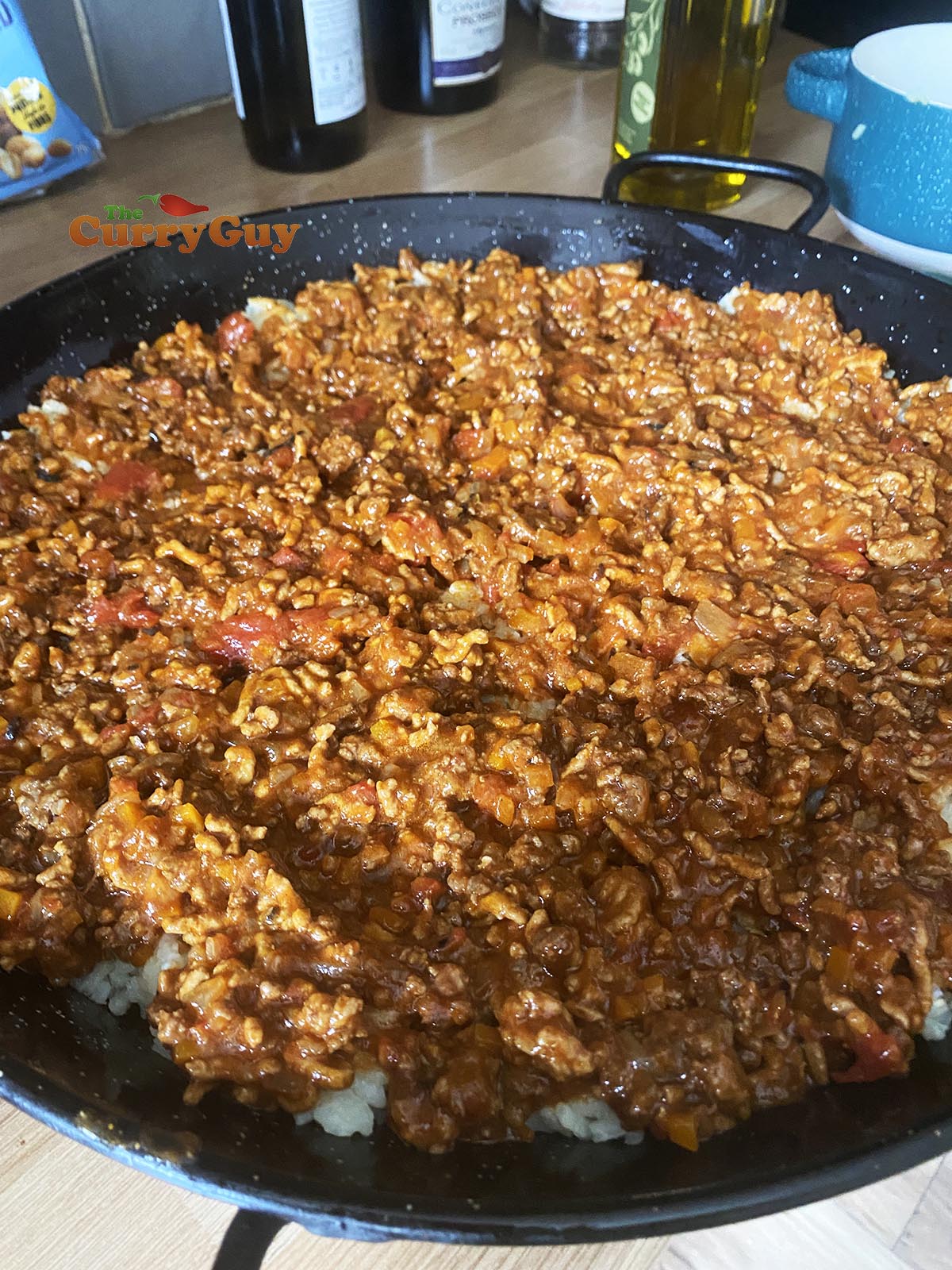Topping the cooked rice with the meat sauce.
