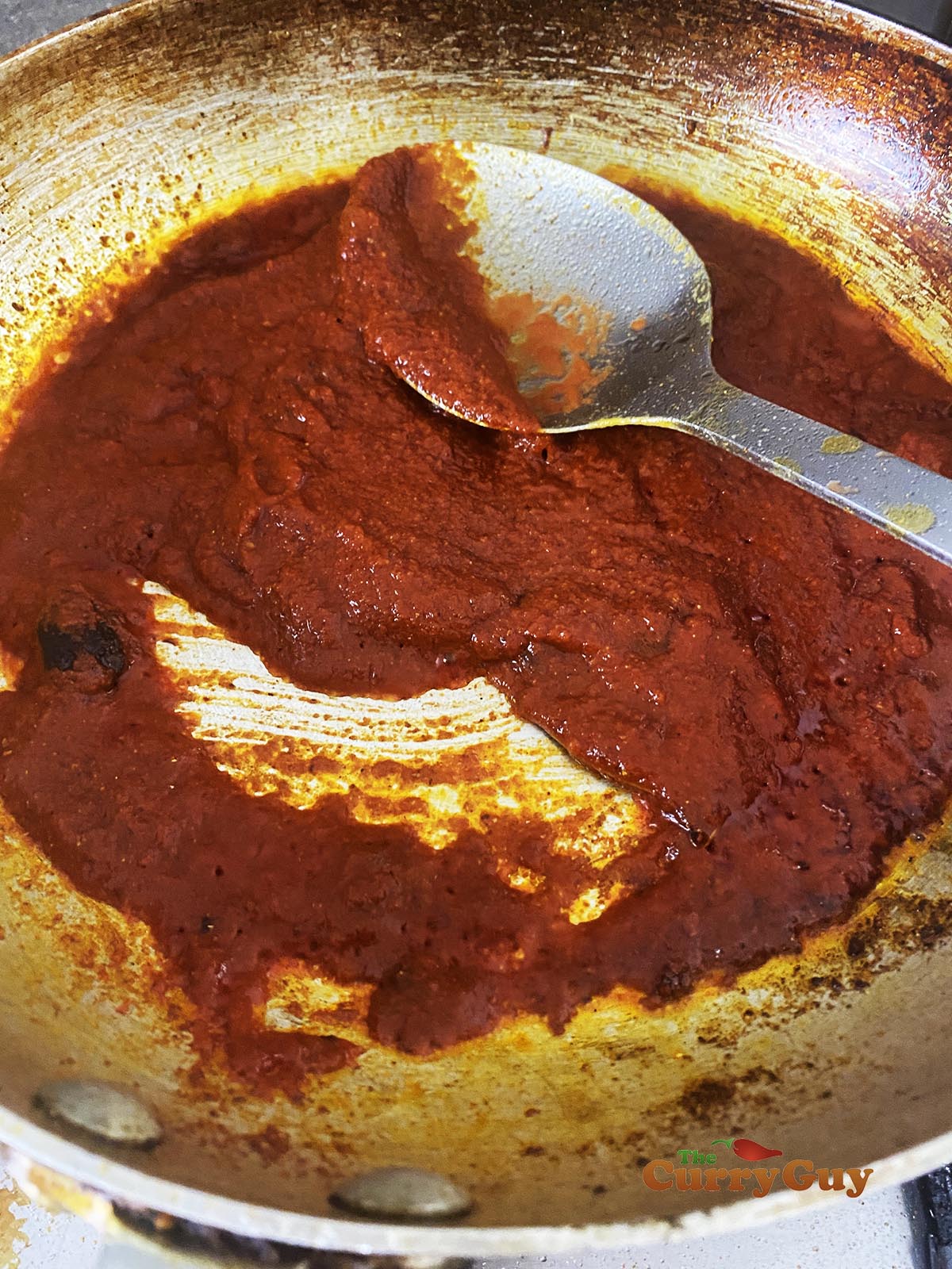 Adding tomato purée to pan