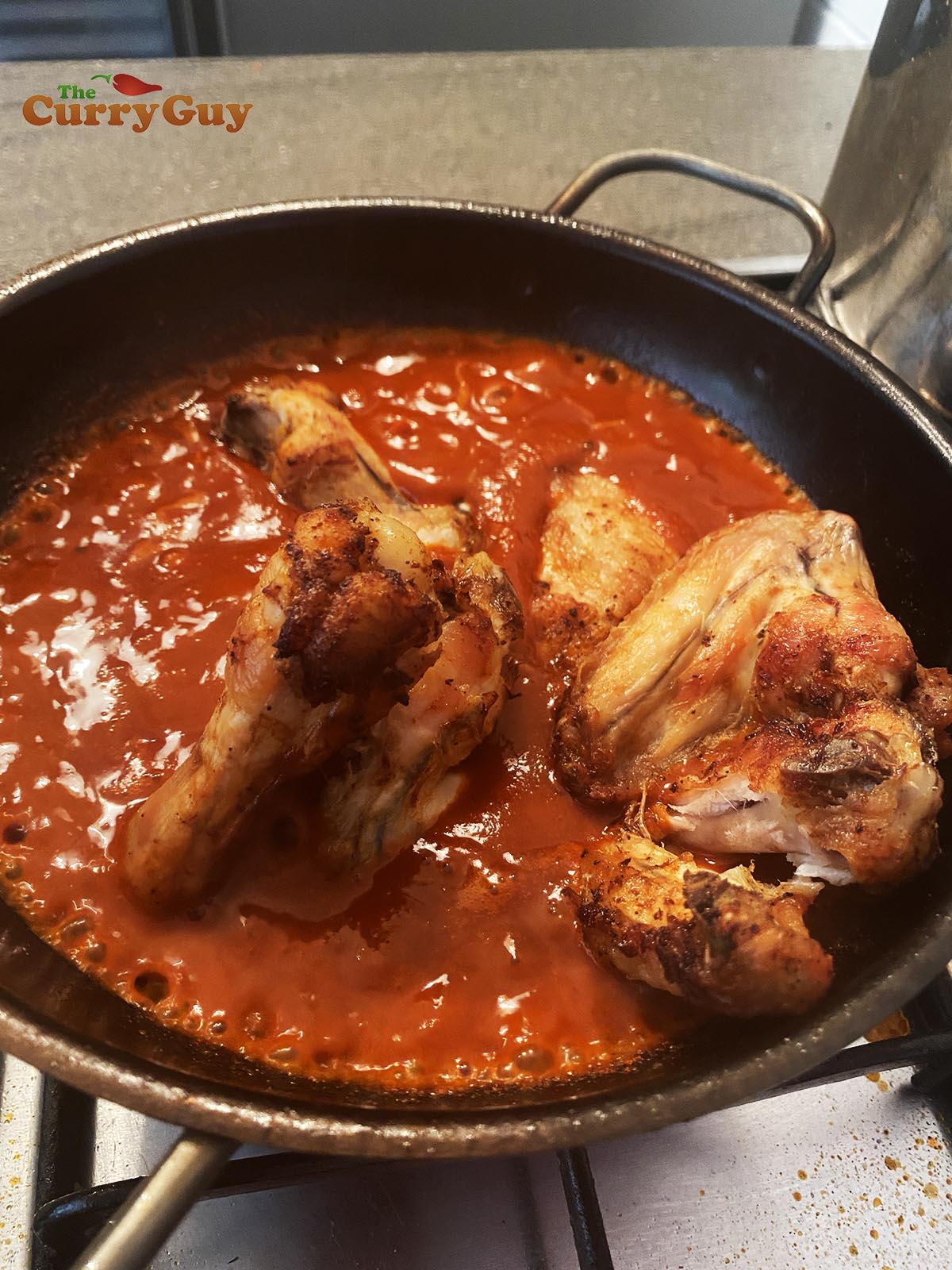 Adding chicken wings to sauce.