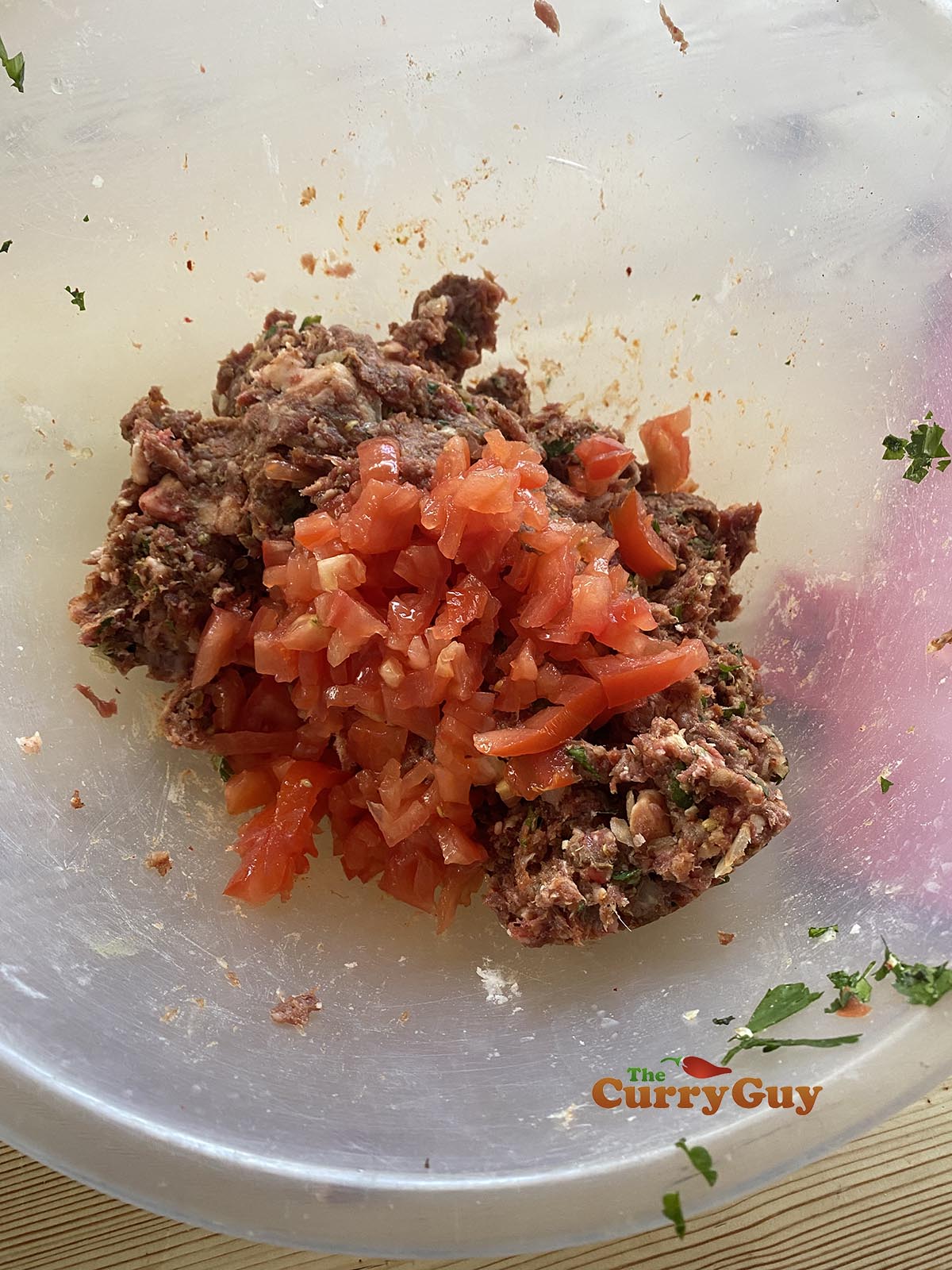 Adding tomato to meat mixture