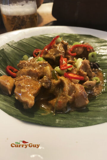 Rendang curry with chicken presented on a banana leaf.
