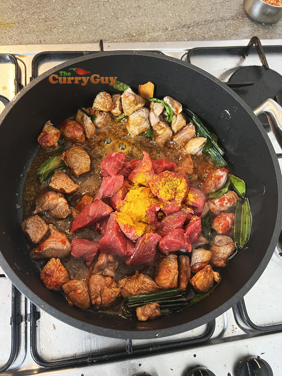 Adding beef, ground turmeric and chilli powder to pan