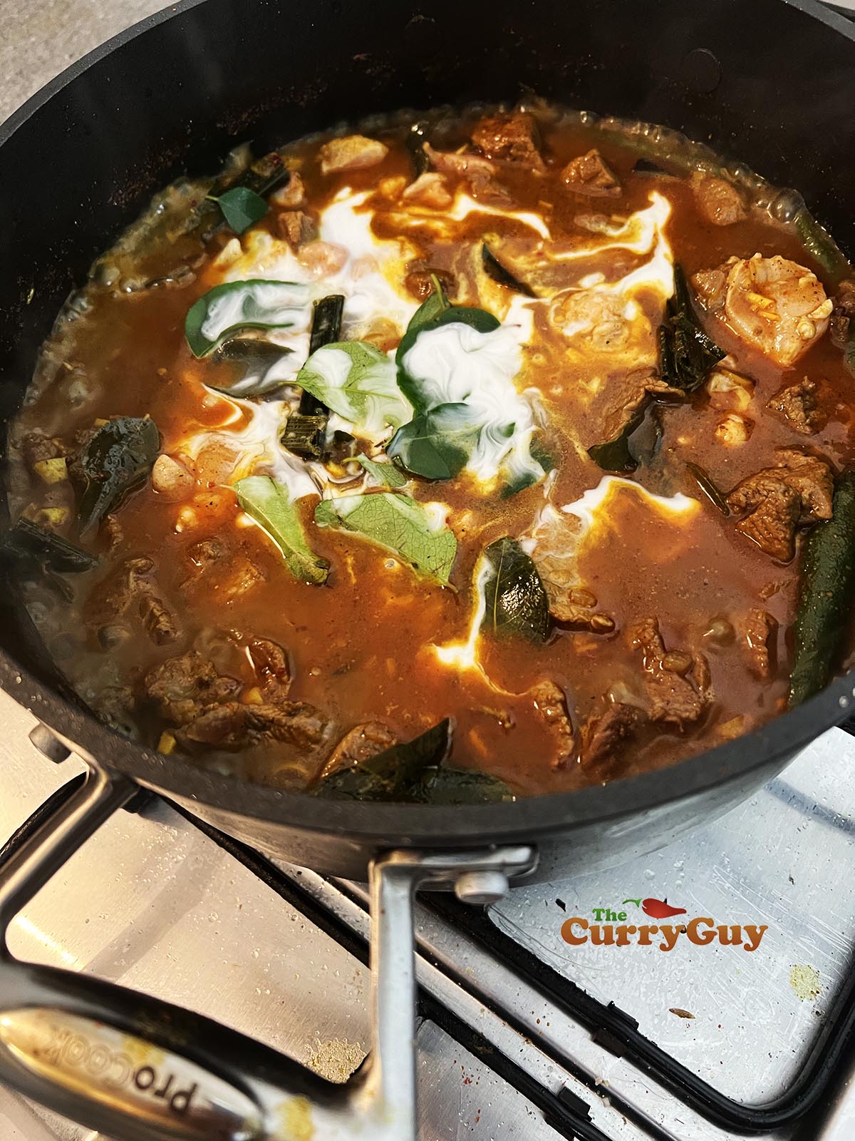 Adding coconut milk, tamarind, curry powder and black pepper to pan