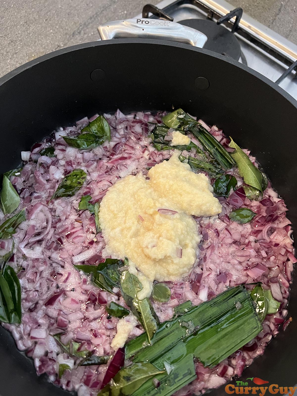 Adding garlic and ginger paste to curry