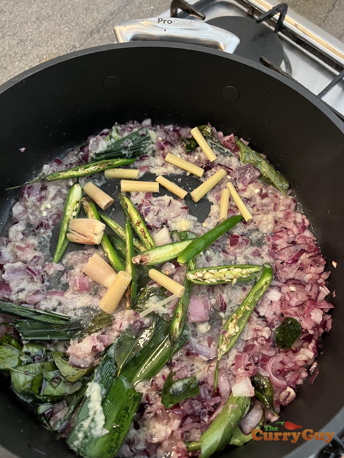 Adding lemongrass and sliced chillies to pan
