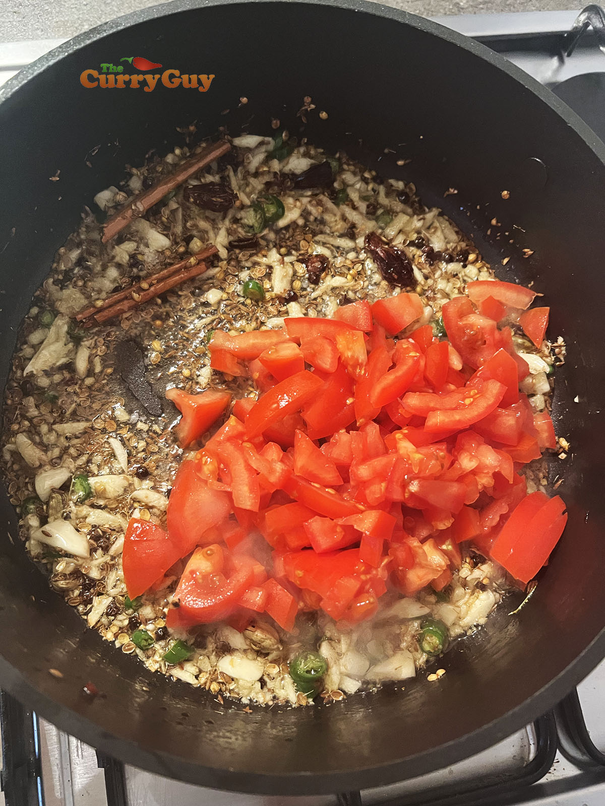 Adding garlic, ginger, chillies and tomatoes to pan