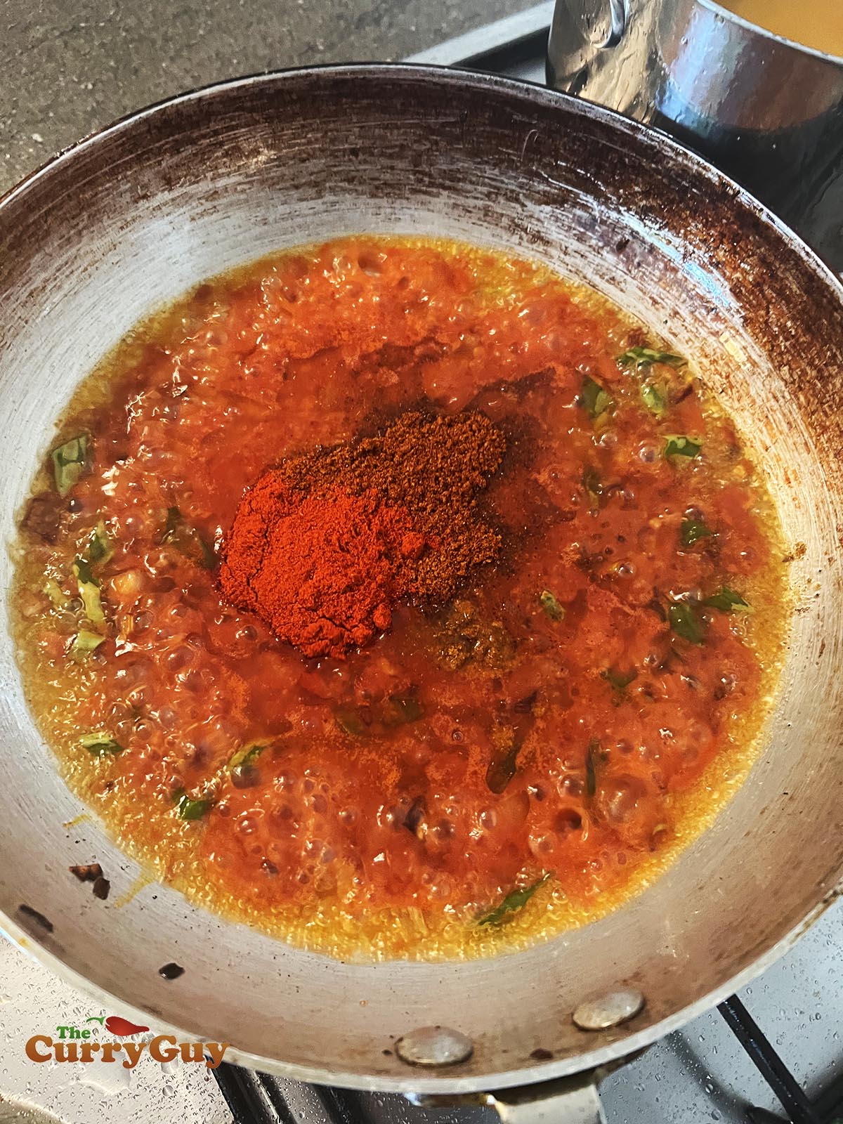 Adding tomato puree and spices to pan