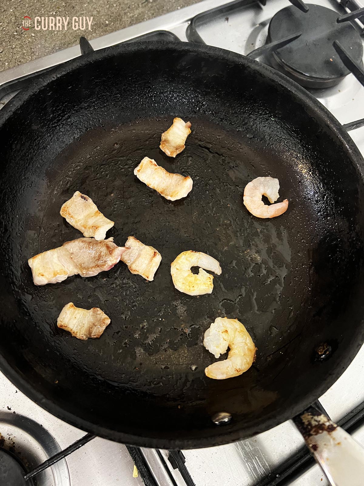 Cooking the shrimp and pork through in a pan. 
