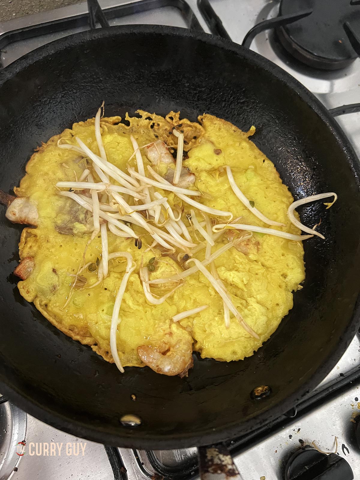 Adding bean sprouts to a cooked banh xeo. 