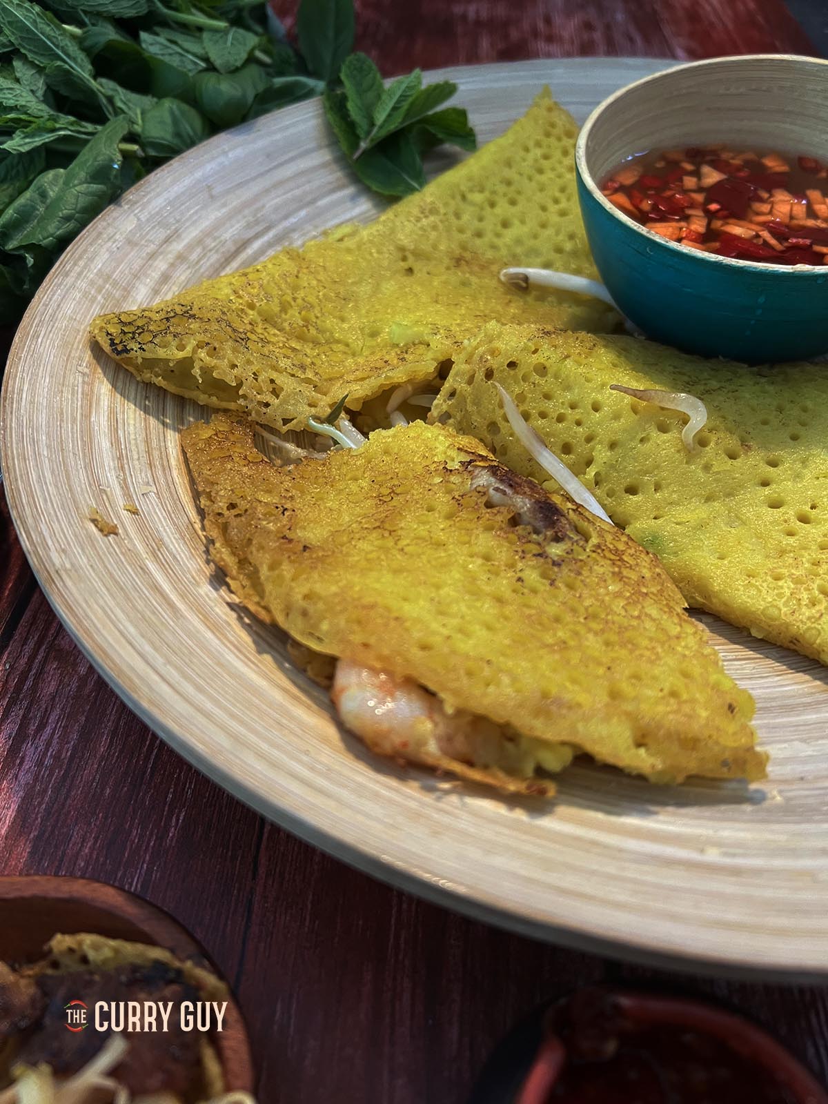 Banh xeo on a serving plate with sauce.