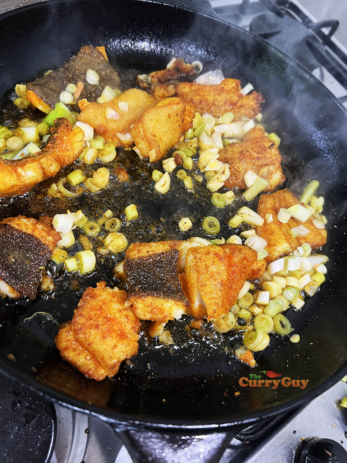 Adding garlic, chillies and spring onions to pan