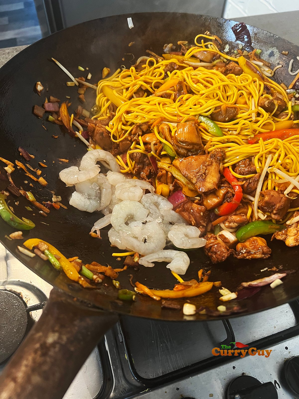 Adding prawns and sauce to wok