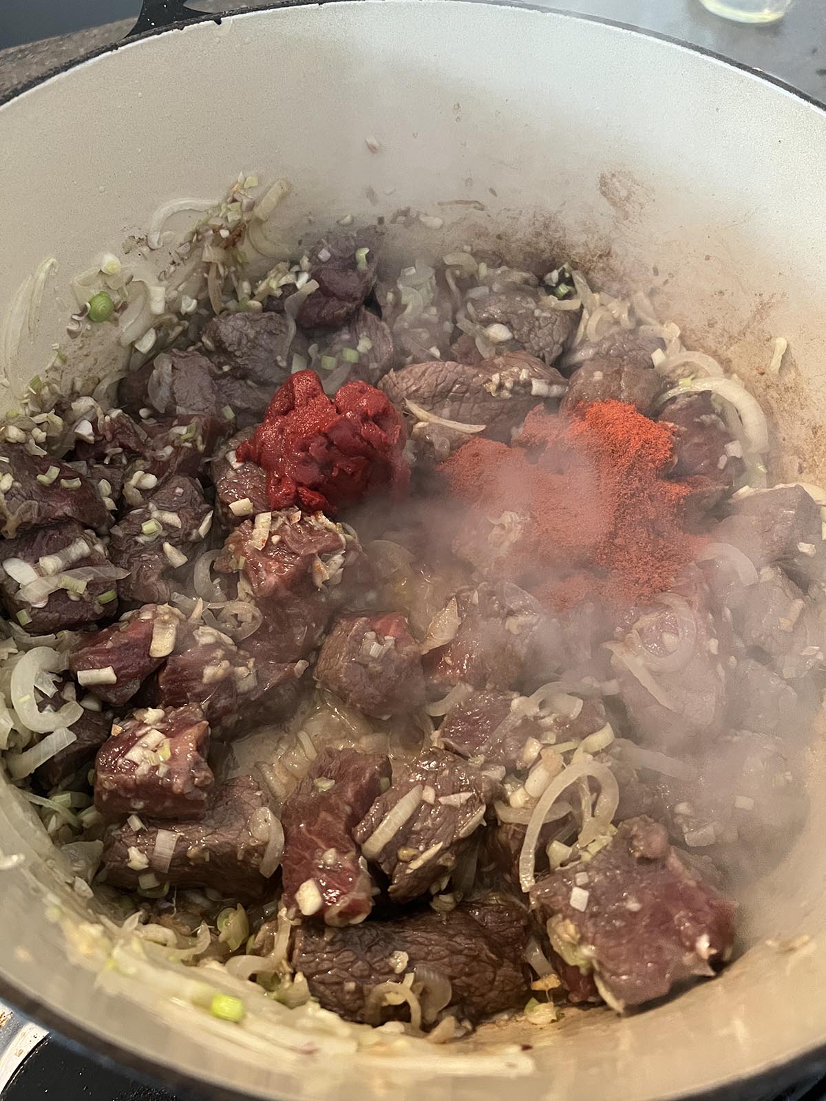 Adding tomato paste and chilli powder to pan