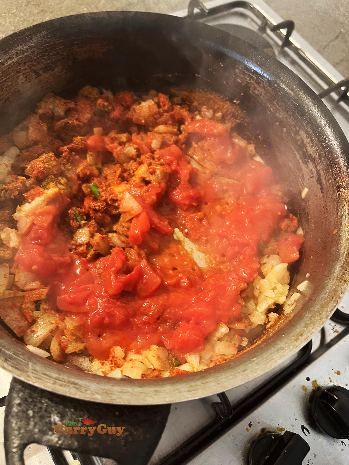 Adding the ground spices and chopped tomatoes