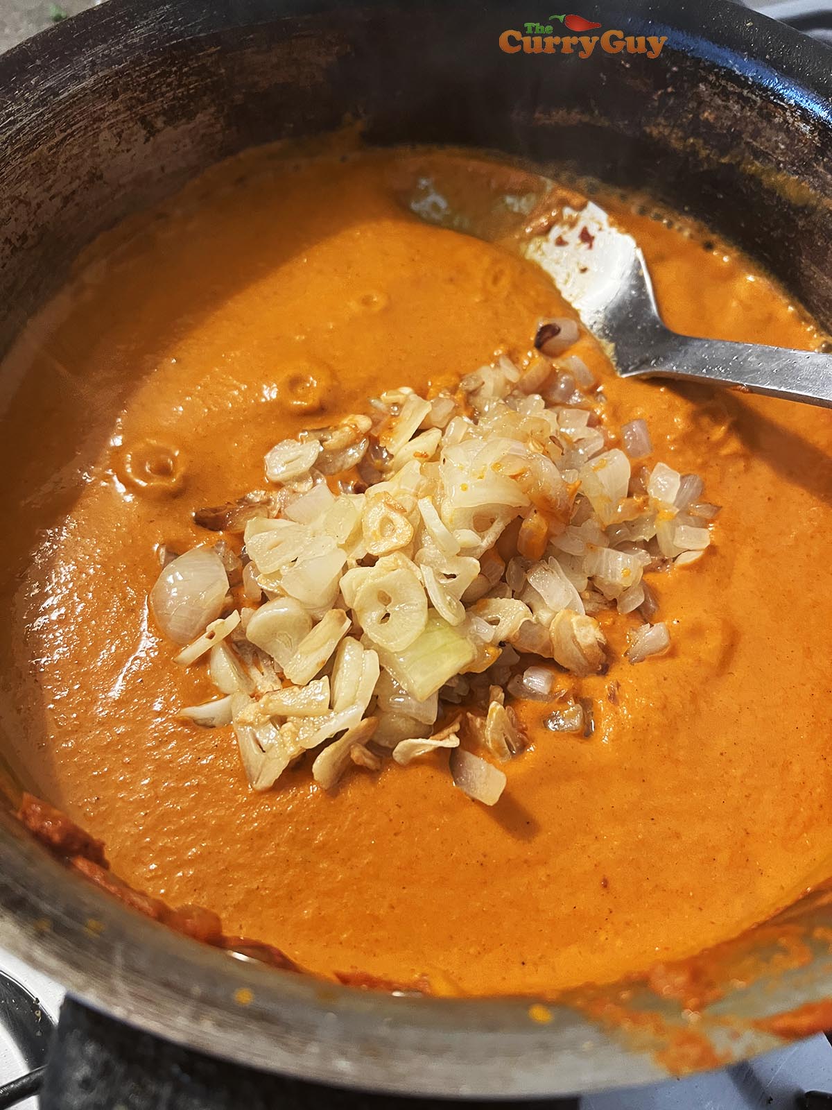 Adding fried garlic and onions to the sauce.