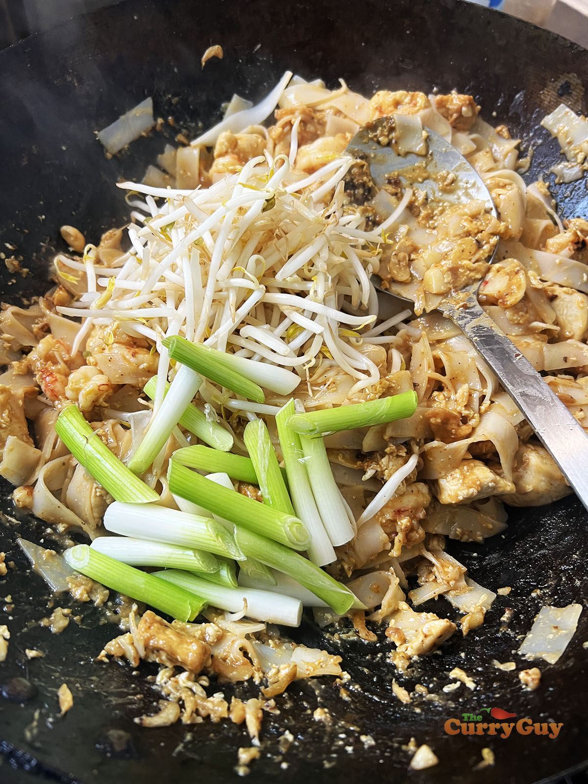 Stirring spring onions (scallions) and bean sprouts to the wok