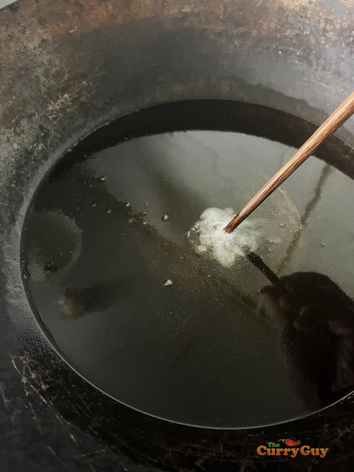 Testing the oil to ensure it is hot enough to fry.