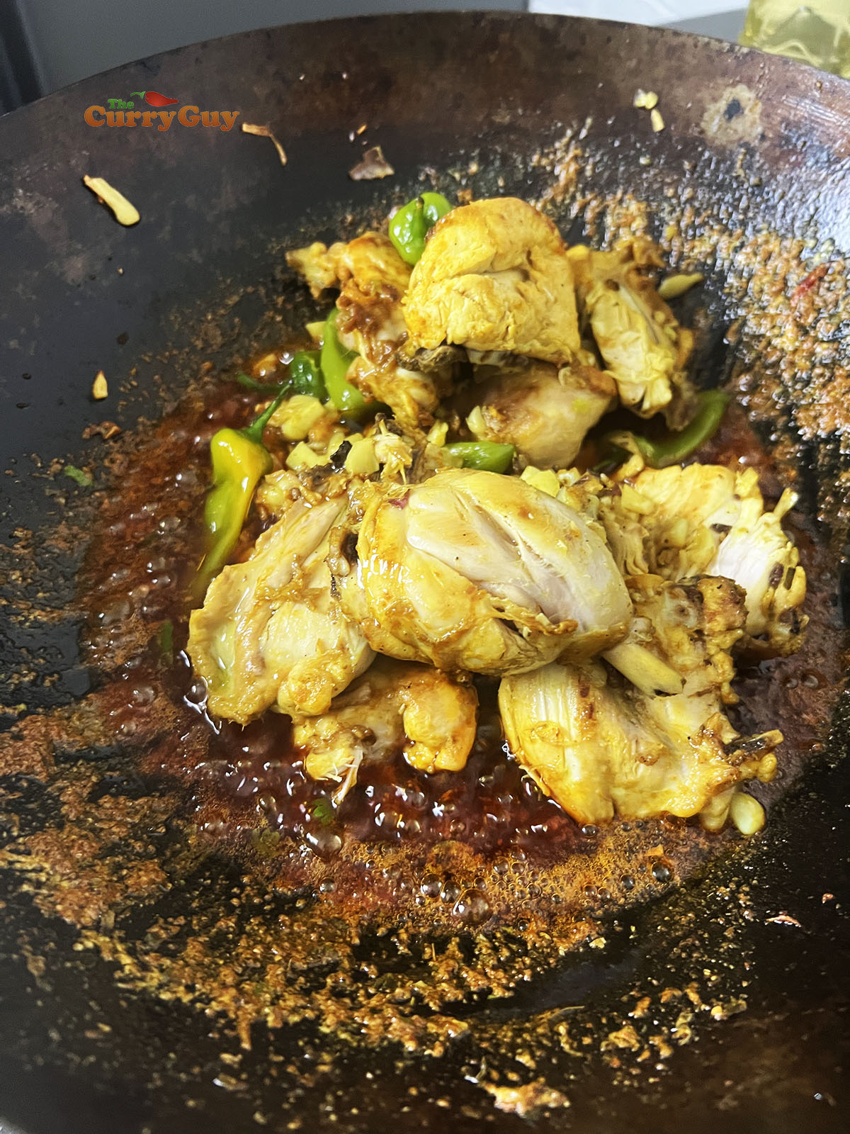Returning the whole chillies, garlic and chicken to the pan