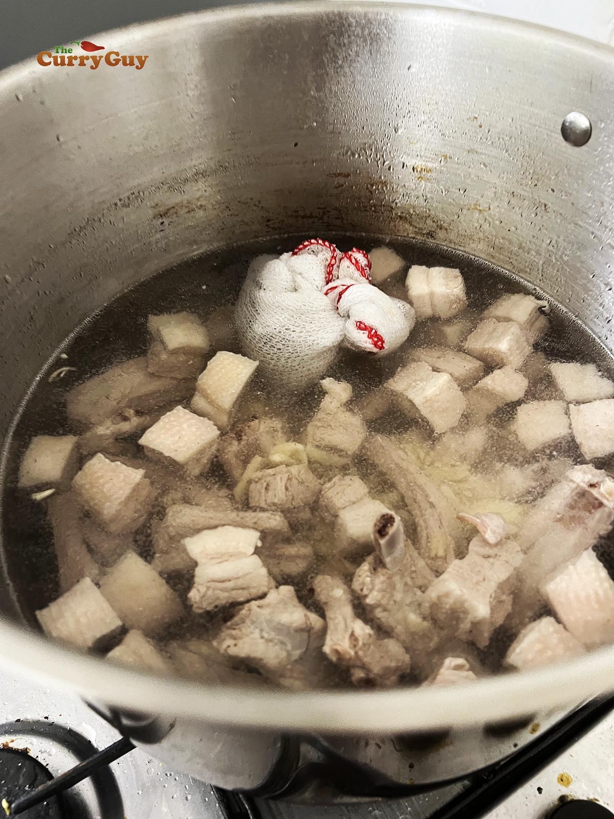 Adding pork and water to the pot.