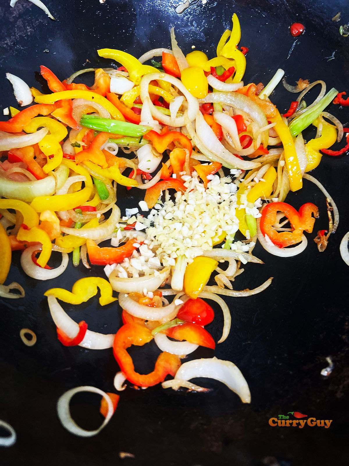 Adding garlic, ginger and chillies to the wok