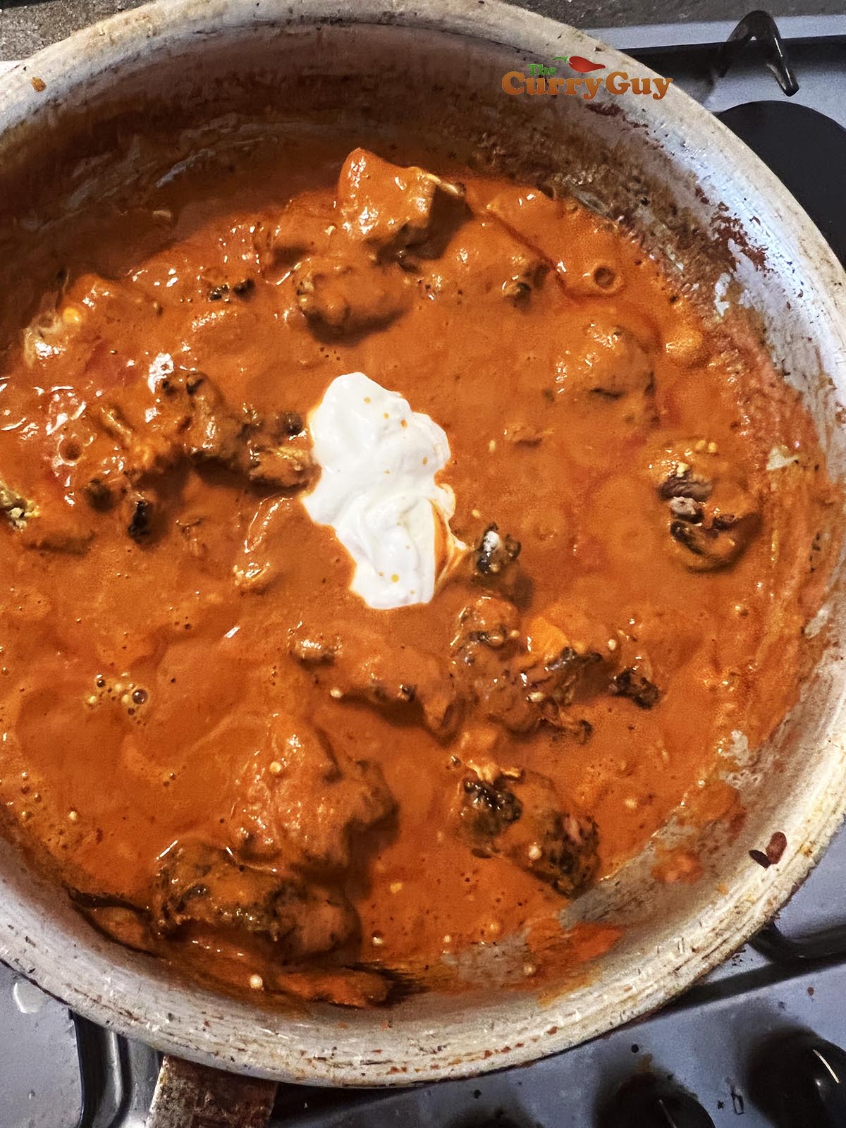 Stirring yoghurt into the sauce.