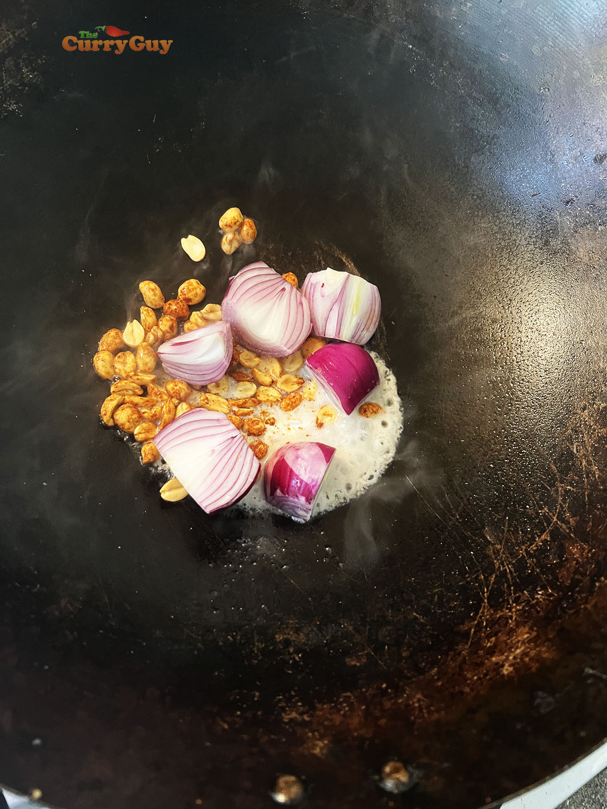 Adding peanuts and onions to the wok