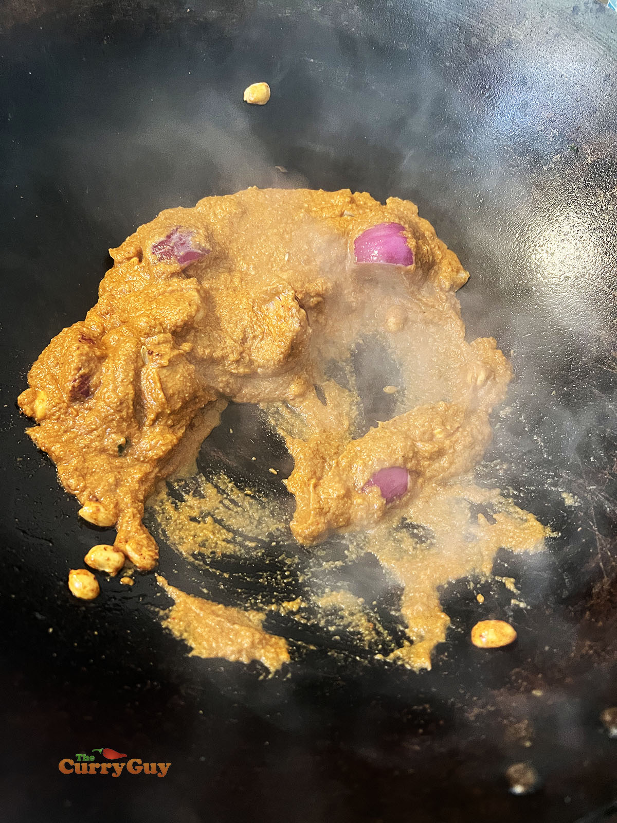 Adding the massaman curry paste to the wok