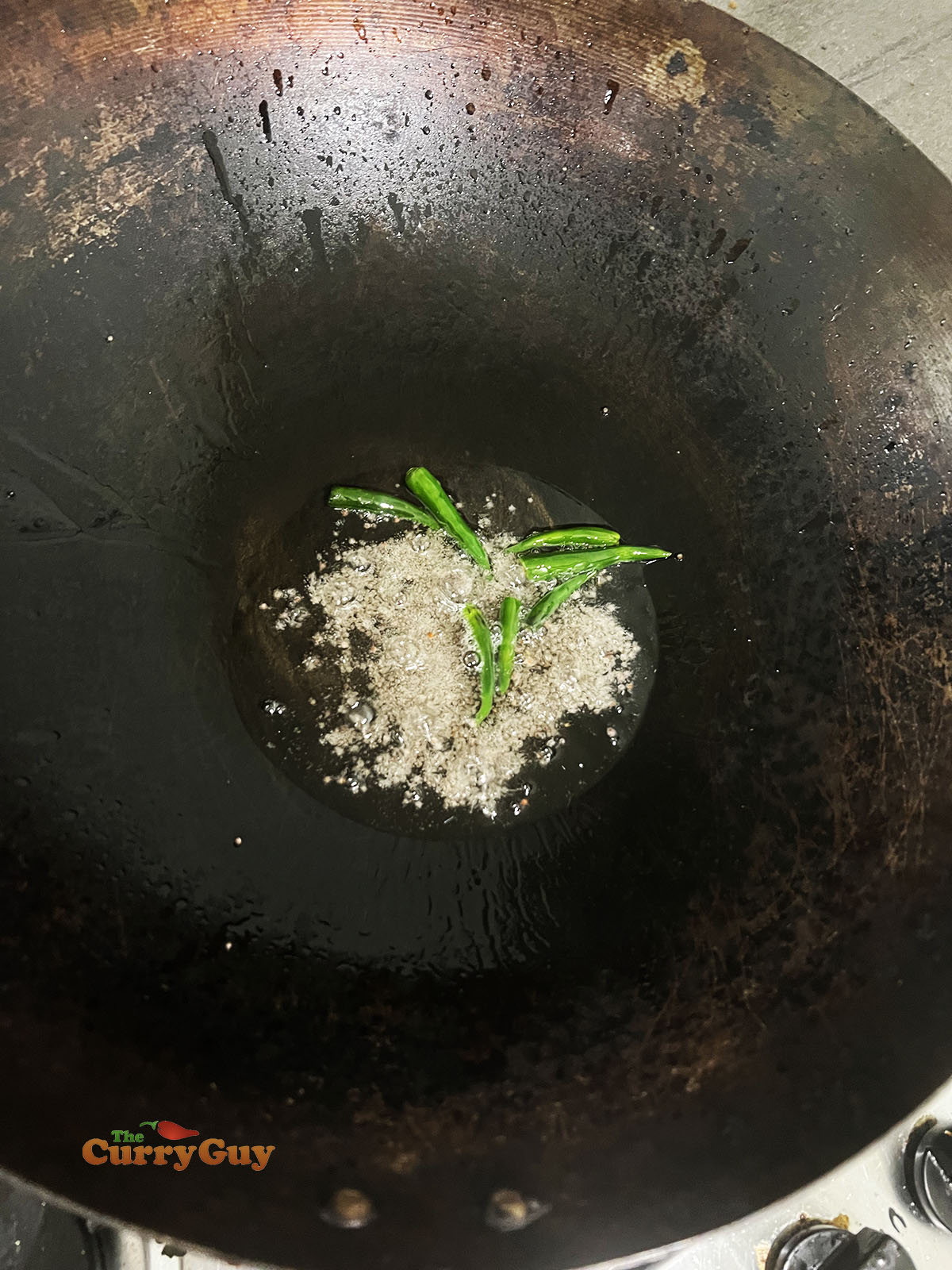 Adding mustard seeds and chillies to the wok