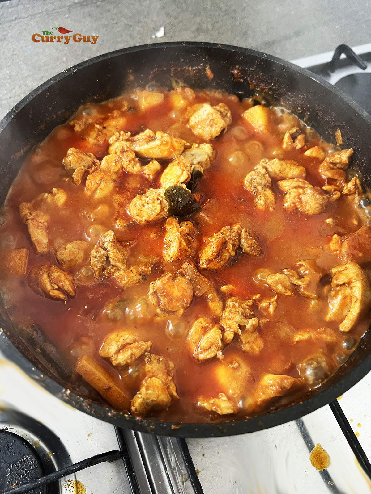 Simmering the chicken and vegetables in the sauce