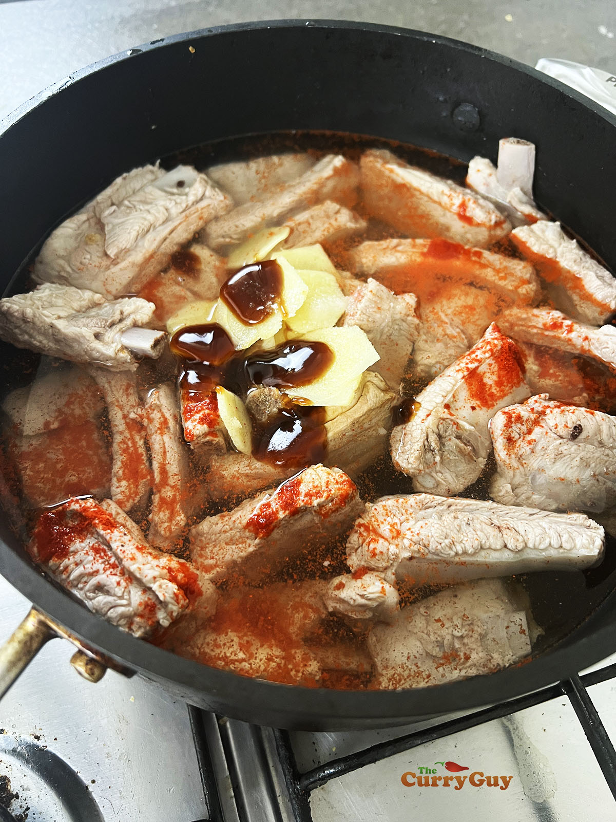 Adding spices and sauces to the pan with the ribs.