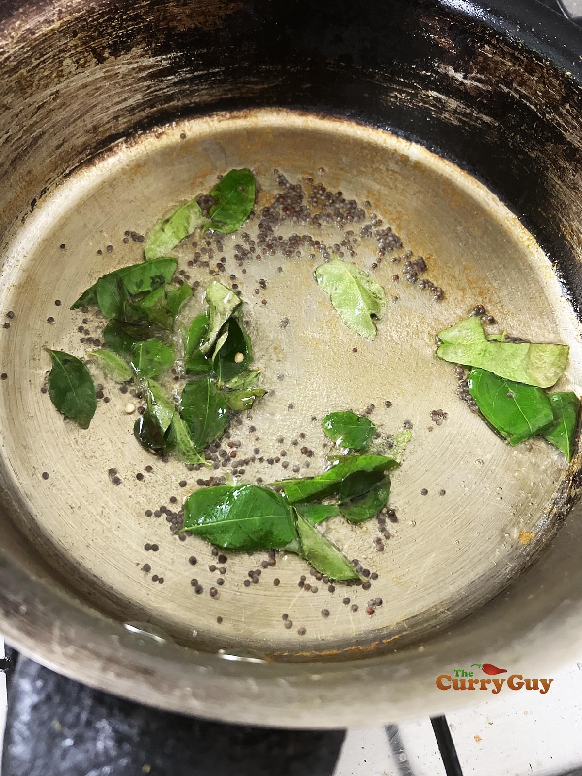 Adding curry leaves and mustard seeds to the pan