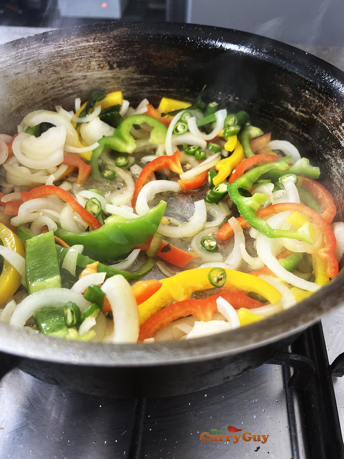 Stirring sliced onions and bell pepper to the pan