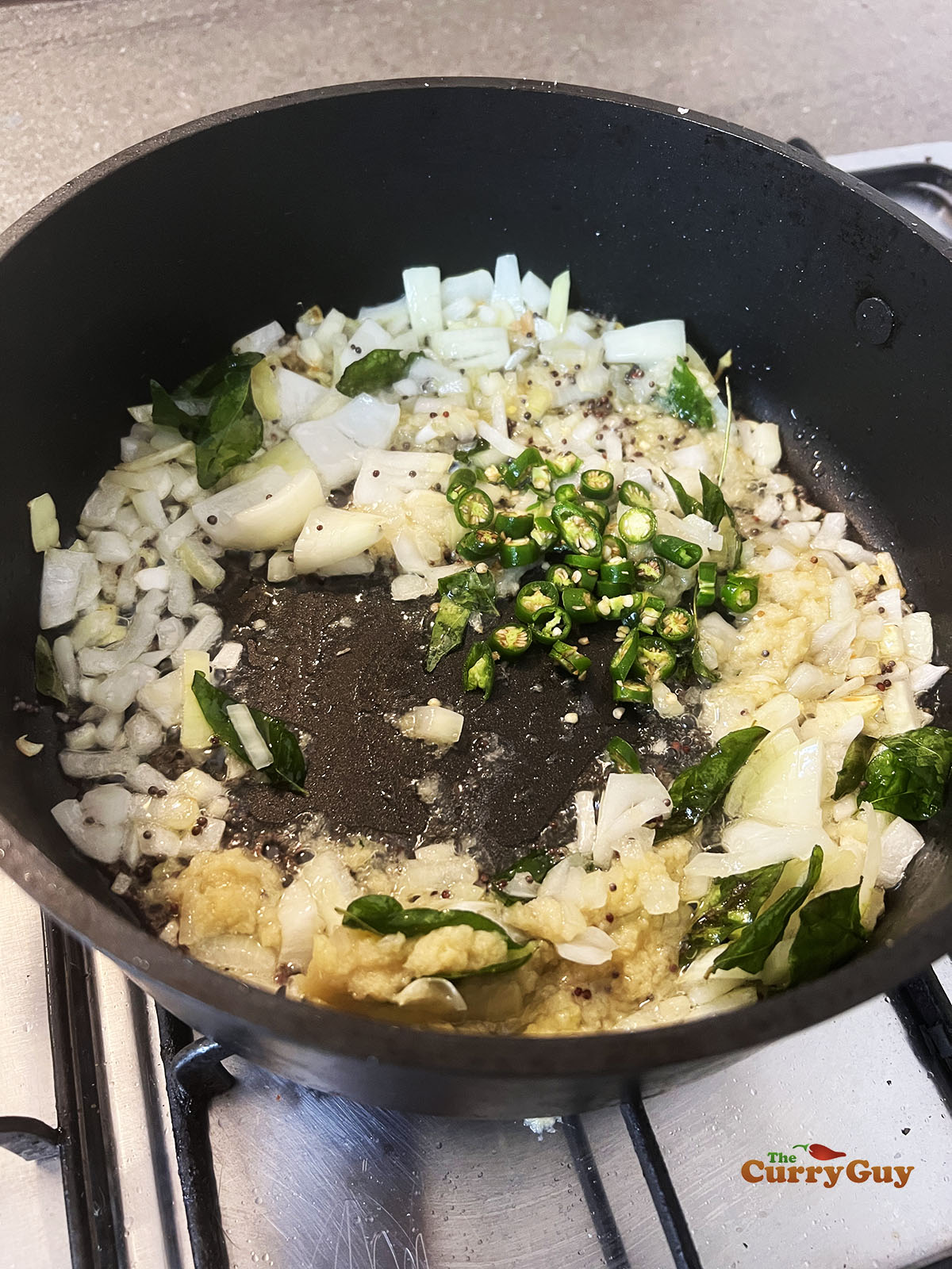 Adding garlic and ginger paste and chillies to the pan