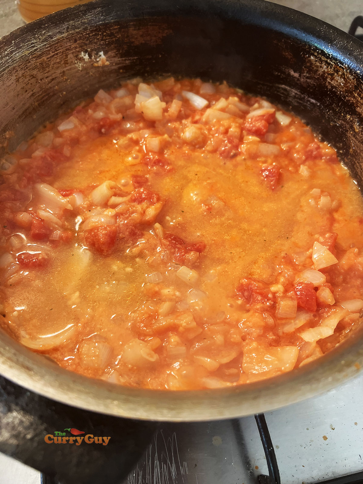 Adding chopped tomatoes and stock to the pan