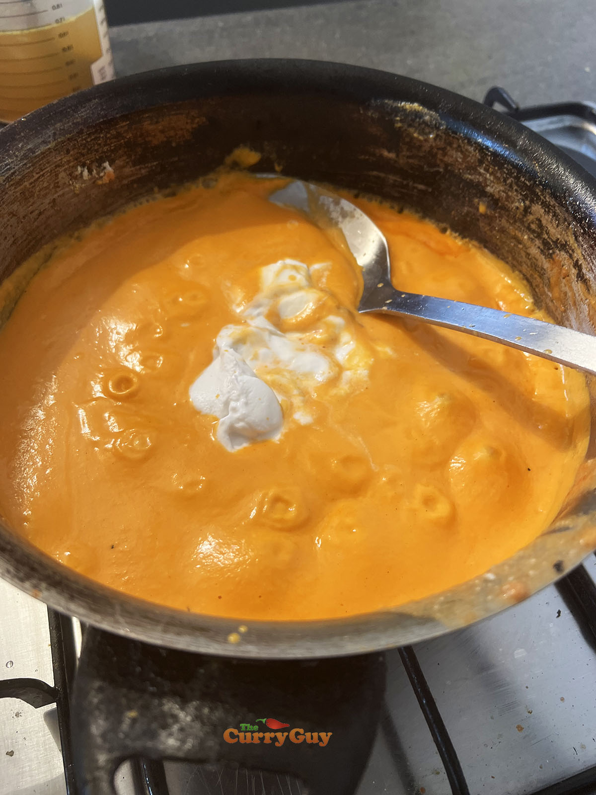 Returning the blended sauce to the pan and adding coconut cream.
