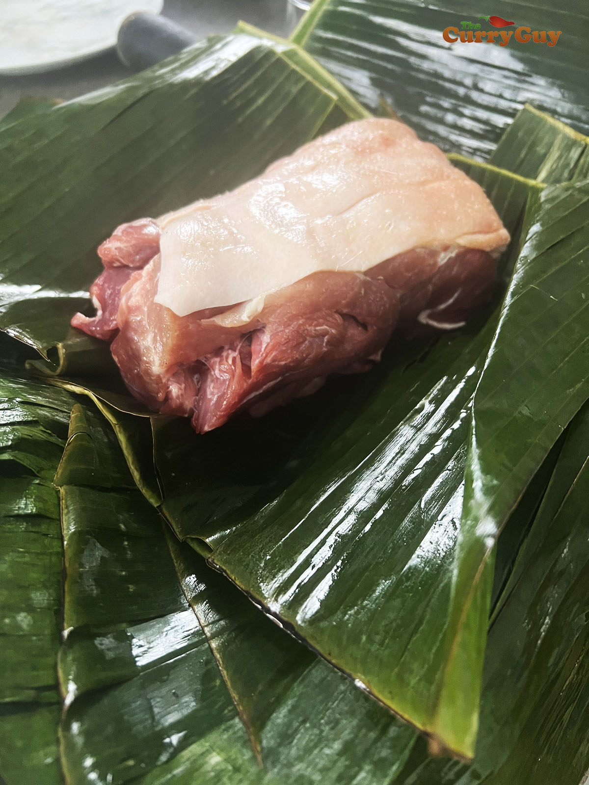 Pork resting on banana leaves.