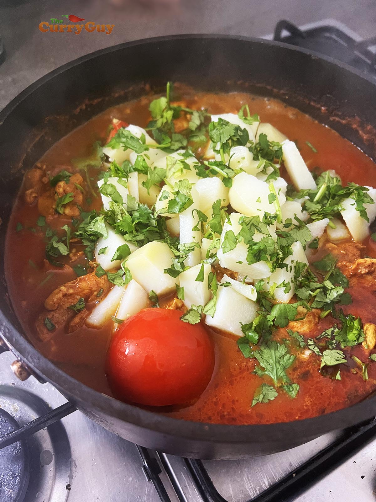 Adding cooked potatoes to the pan and garnishing with coriander (cilantro)
