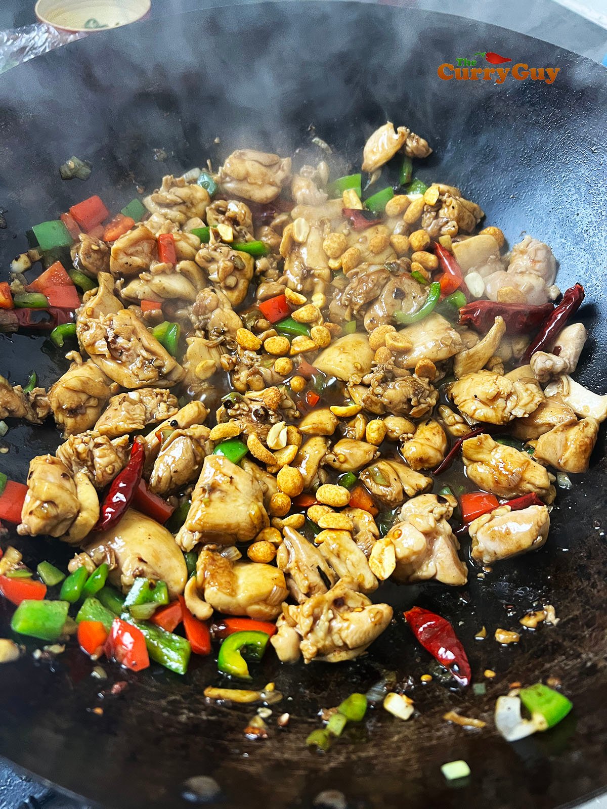 Returning the par-cooked chicken to the wok.