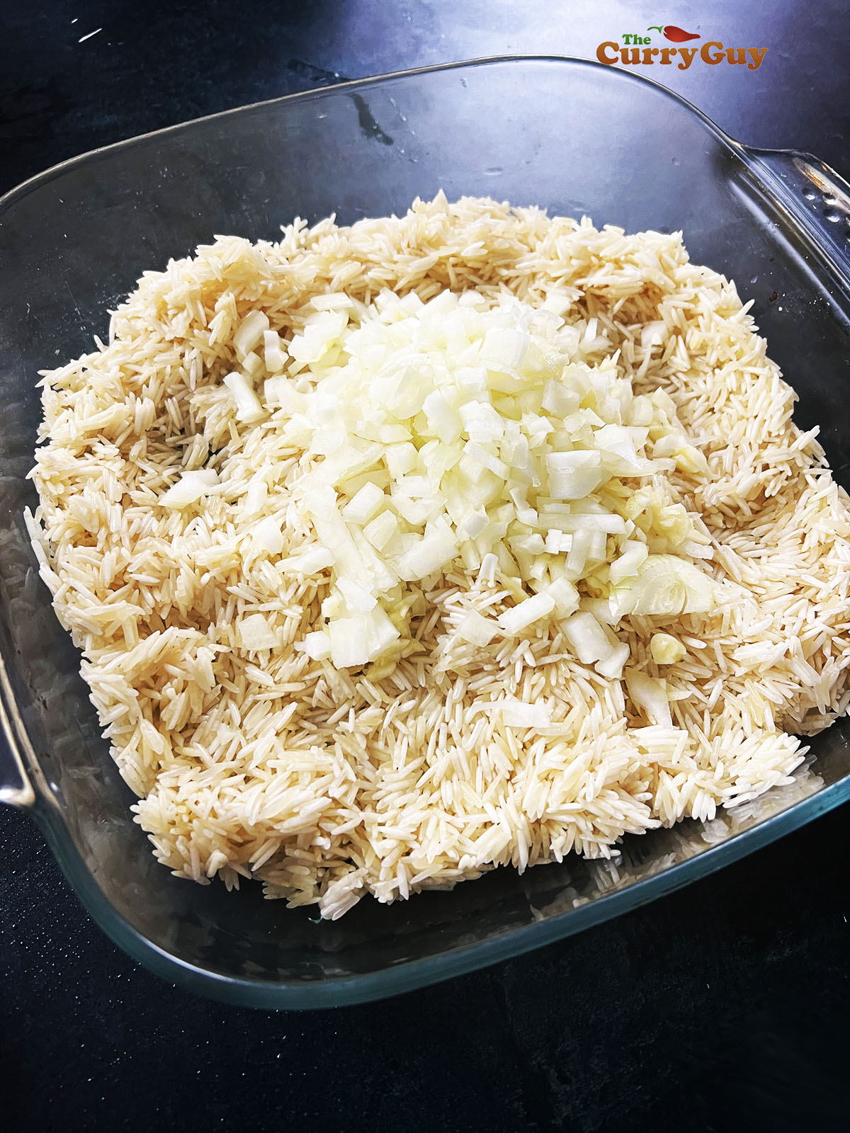 Rice in casserole dish topped with chopped onions. 
