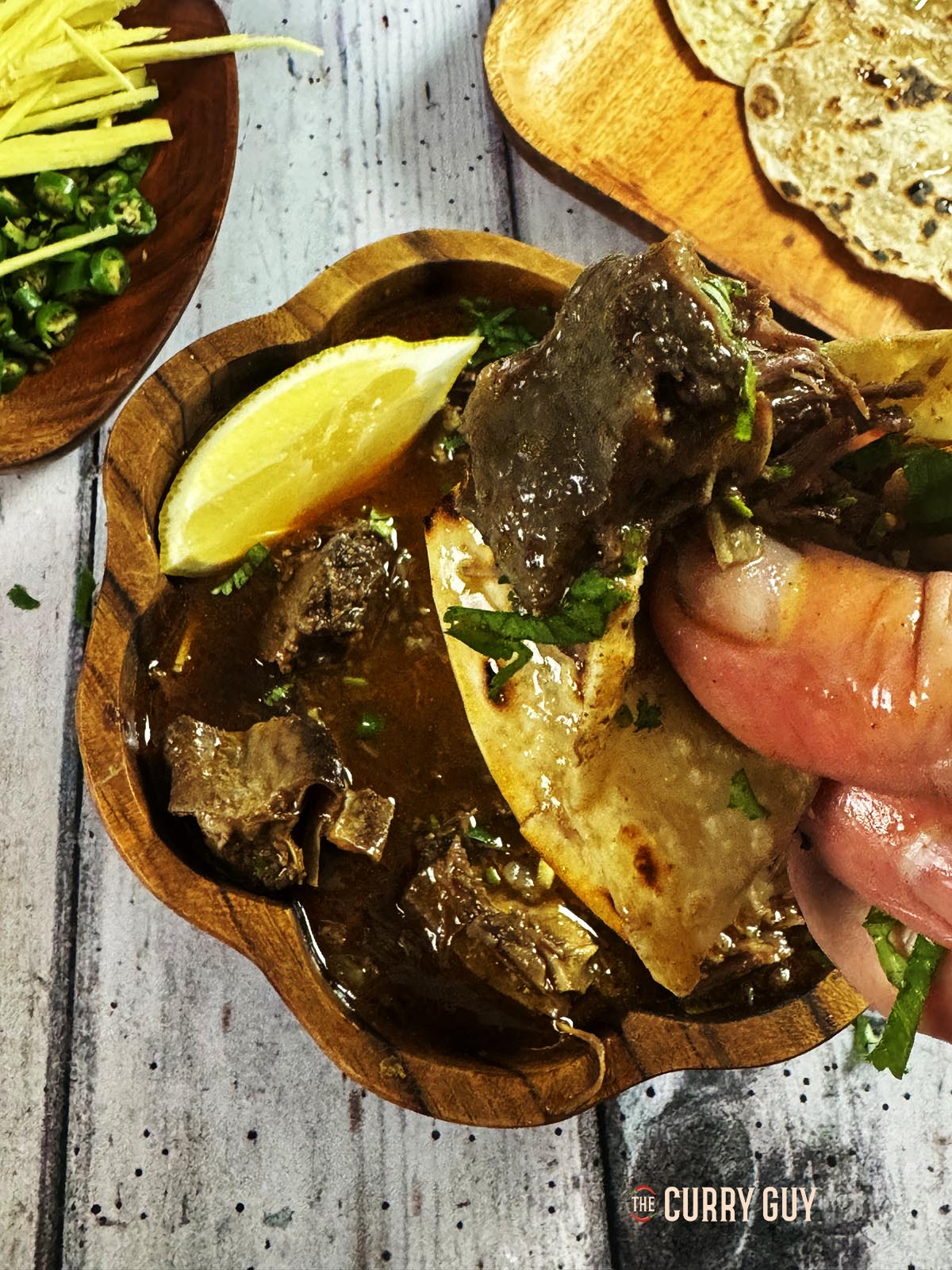 Picking up a piece of the beef with a paratha.