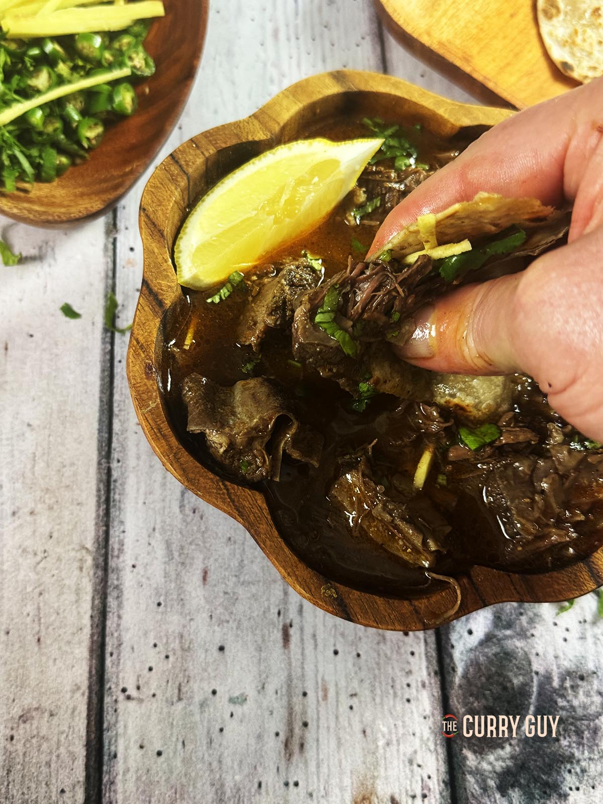 Eating beef nihari by dipping a paratha into the sauce and meat.