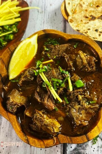 beef nihari in a serving dish, topped with coriander, julienned ginger and green chillies.