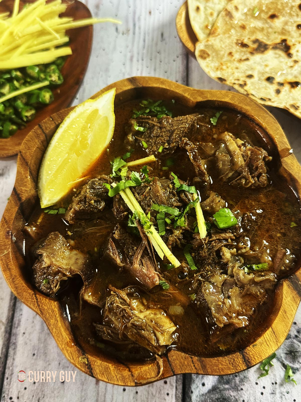 beef nihari in a serving dish, topped with coriander, julienned ginger and green chillies. 