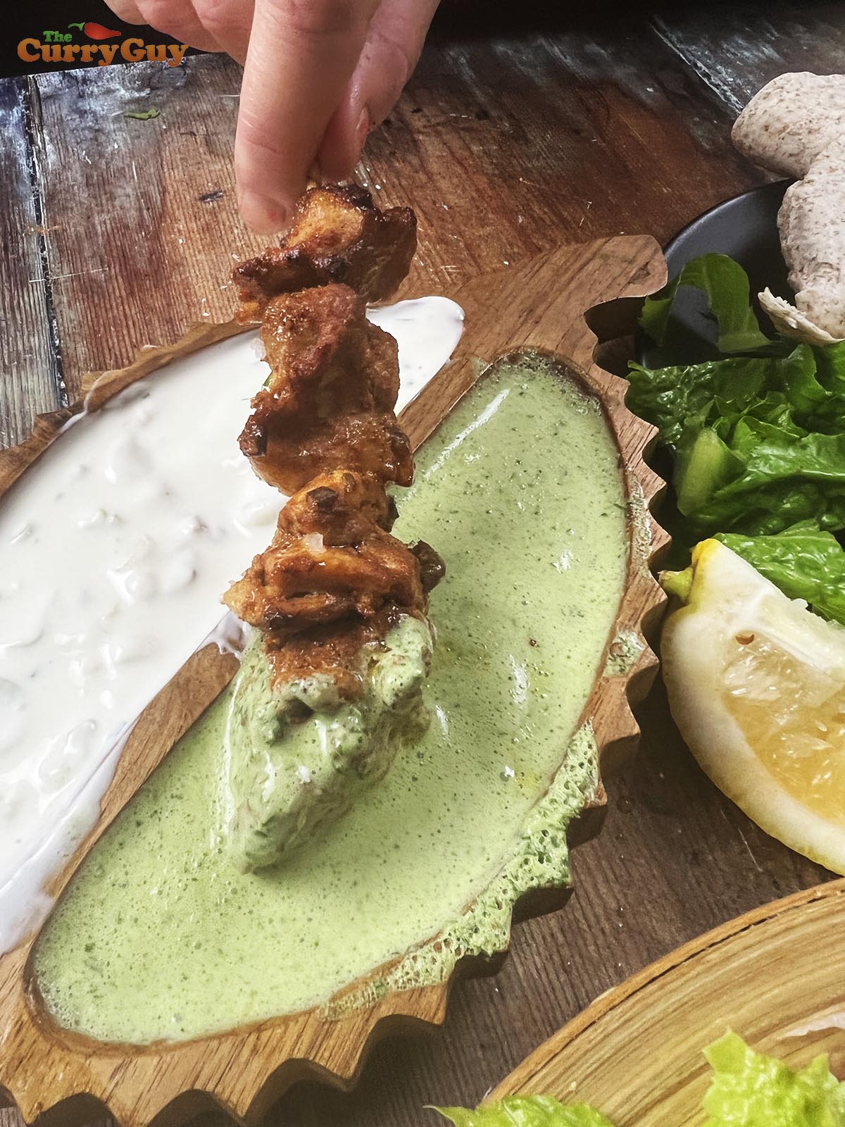 Dipping chicken tikka into a coriander raita.