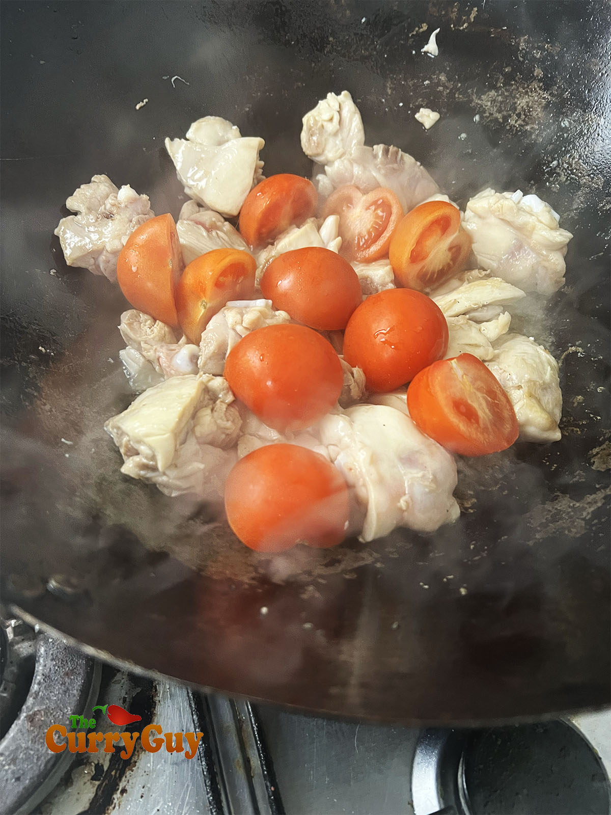 Adding the tomatoes to the karahi pan