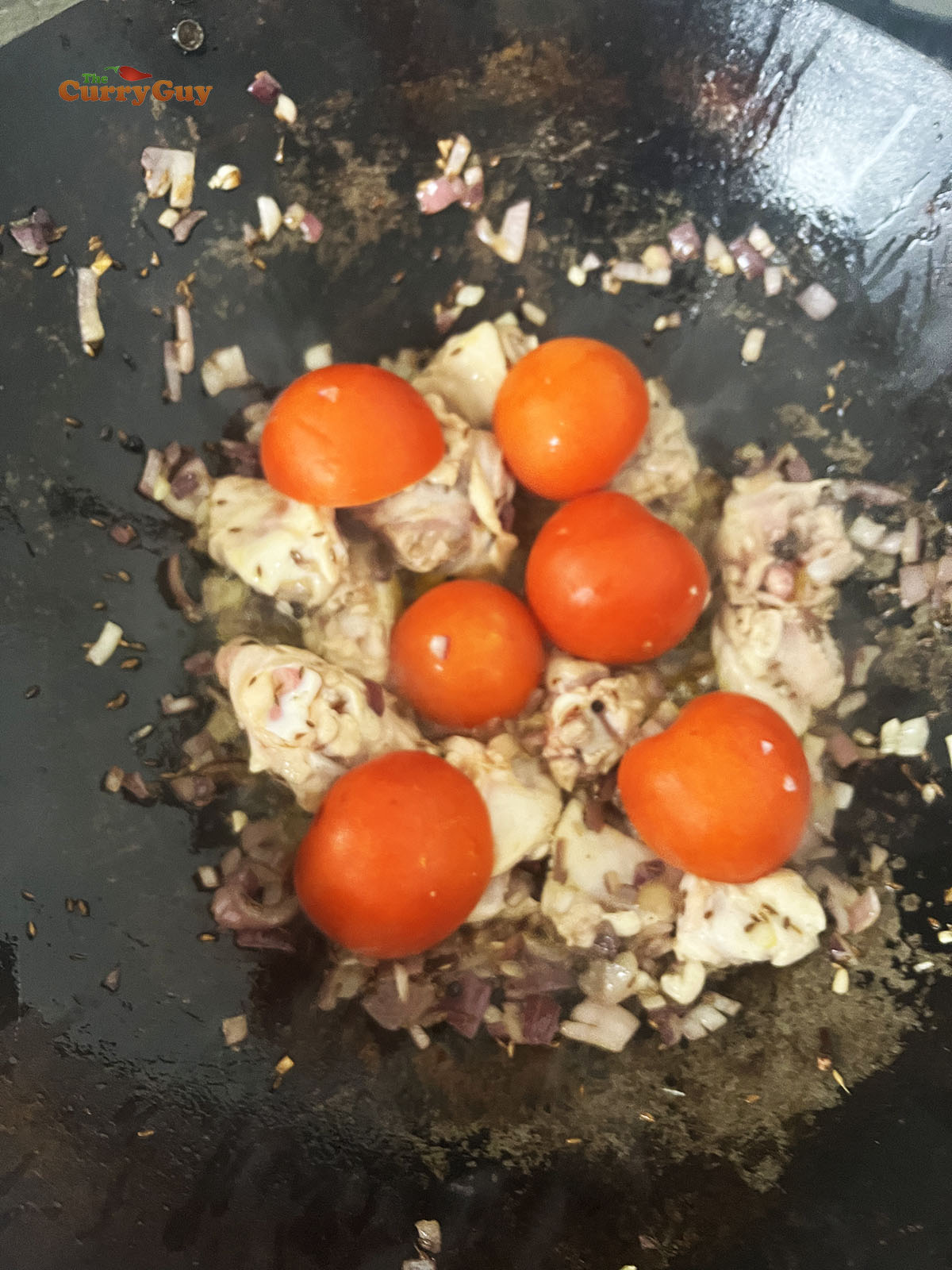 Adding the tomatoes to the pan.