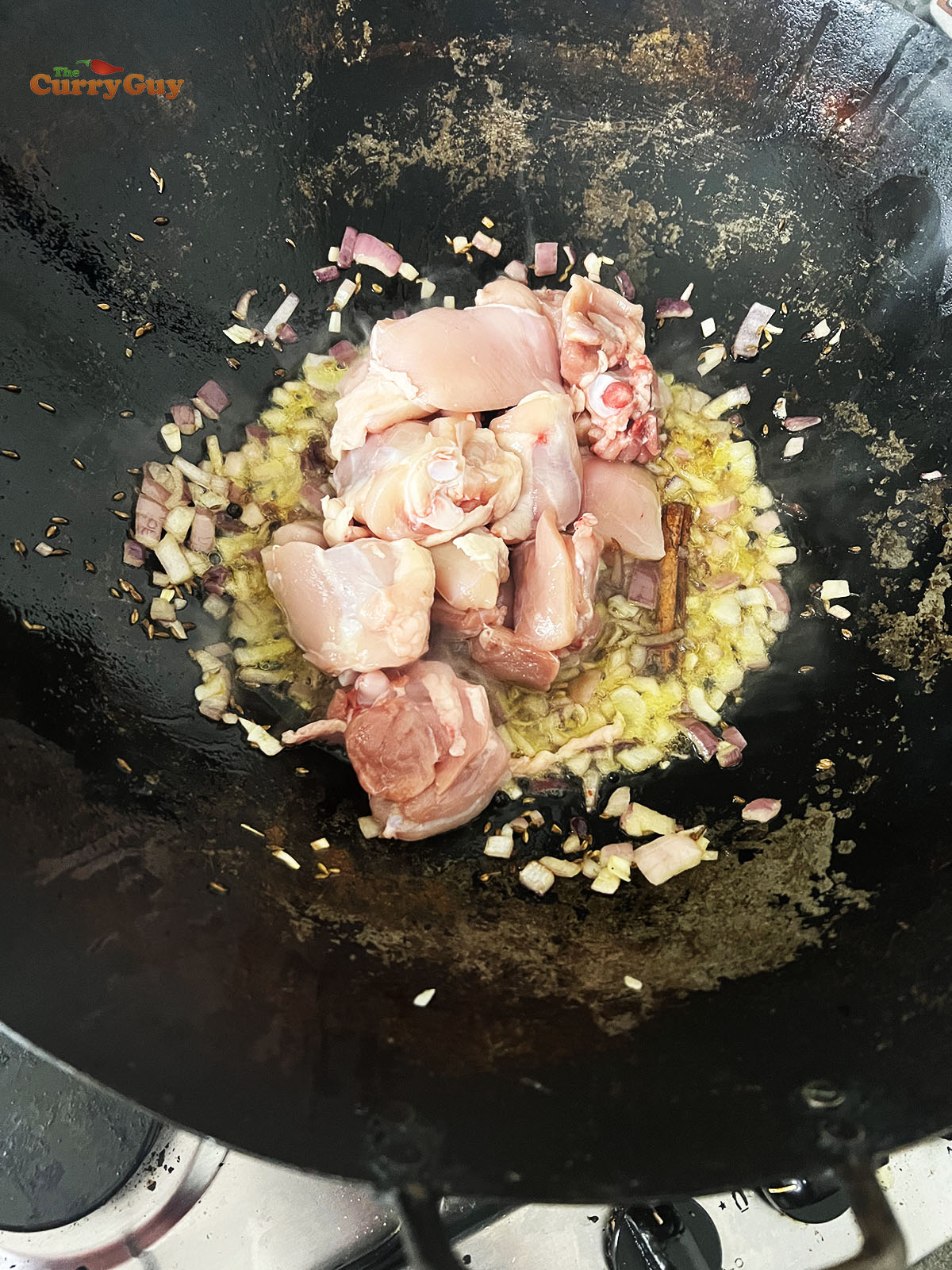 Adding chicken to the pan.